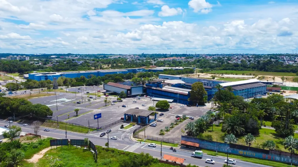 Vista aérea da entrada do campus da Universidade Nilton Lins, com estacionamento e prédios azuis